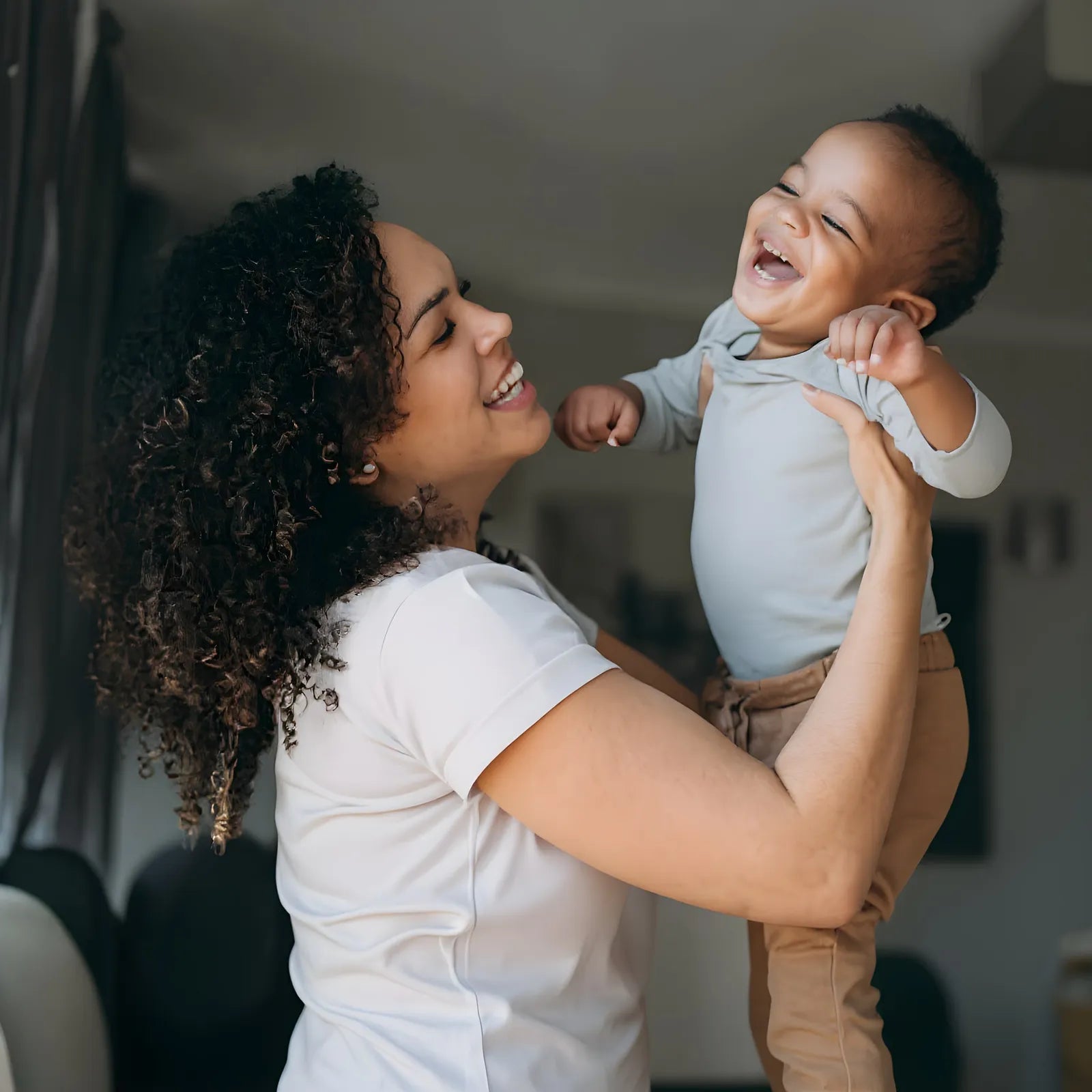 A mother holding her laughing baby, on vintage film